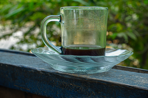 A glass on top of a pisin filled with coffee that had run out.
