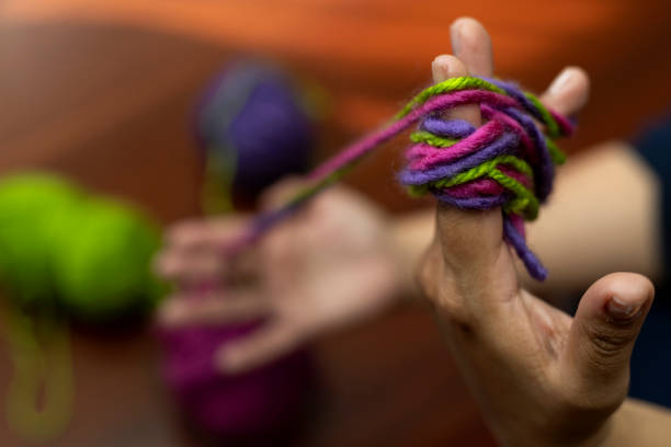 羊毛繊維のボールを広げてさまざまな色で織る手の接写。余暇と自由時間のコンセプト - wool close up knitting fiber ストックフォトと画像