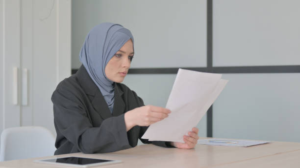 istock Muslim Businesswoman Reading Documents at Work, Paperwork 1594258780