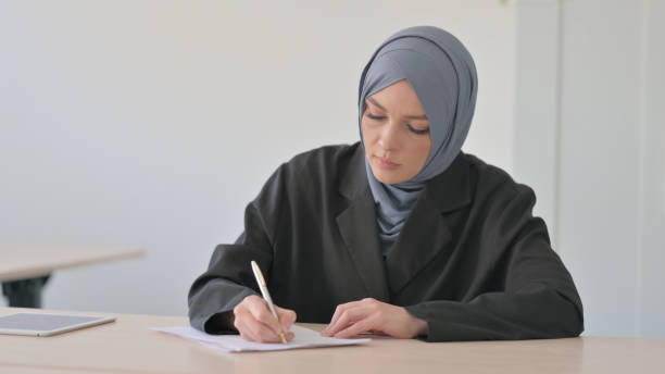istock Arab Businesswoman Writing at Work, Paperwork 1594266180