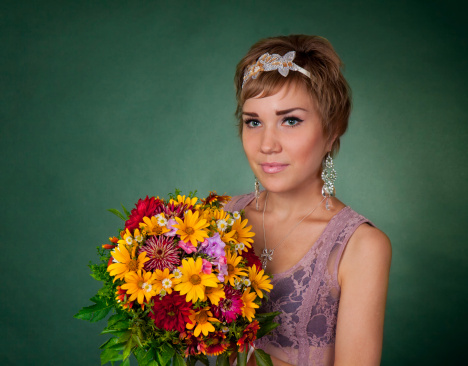 Pretty girl holding bunch of flowers and looking at camera