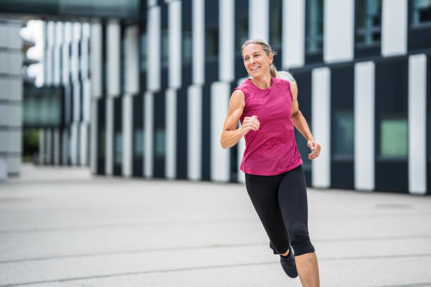 istock happy woman jogging fast between modern buildings 1594344672