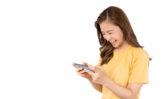 Excited Young Asian woman playing online game on smartphone isolated on white background copy space She get fun and winning victory moment Enjoy and fun relax time Girl streamer playing video game