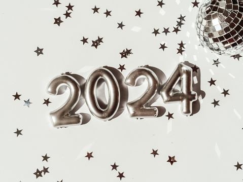 Greeting card - happy new year with numbers 2024 and silver star shape glitter on light background. Bright holiday concept. Top view. Flat lay