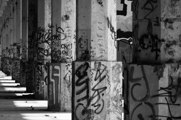 Spray paint on walls glowing with purple neon lights, looking grungy in neglected empty building. Deserted crumbling ghetto illuminated by fluorescent bright light, glowing space.
