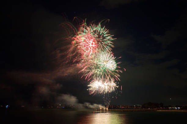 vista aérea de fogos de artifício brilhantes explodindo com luzes coloridas sobre a costa do mar no feriado do dia da independência dos eua - exploding celebration multi colored colors - fotografias e filmes do acervo