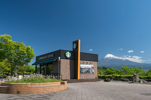 Shizuoka, Japan - April 27, 2023: Starbucks coffee shop at Tomei Highway Fujigawa Service Area with mount Fuji against blue sky in Fuji city.