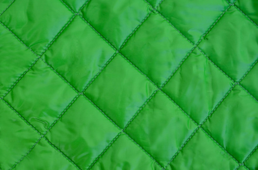Abstract green fabric texture quare seam pattern.Guilted jacket.Empty background for design with copy space.Selective focus.