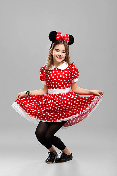 Happy little girl wearing a carnival costume, against a gray background