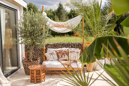 Cozy garden outdoor sofa in boho bamboo style with natural material and linen