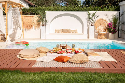 Boho Garden party picnic by the swimming pool on wood patio with food buffet and cushions