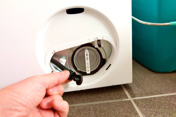 istock Hand touches hose at washing machine, cleaning washing machine filter 1594502036