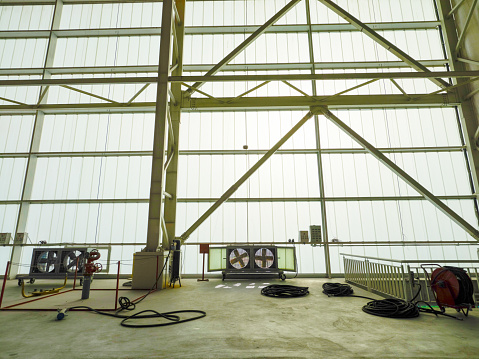 Empty aircraft hangar. Frosted glass side facade. Large ventilation fans. Thick energy cables for airplanes.