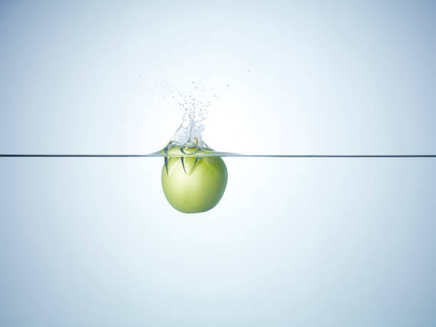 Fresh red apple splashing into water on white background