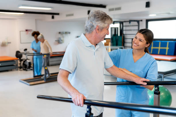 istock Happy senior man feeling proud during physical therapy while walking with the help of parallel bars and his cheerful therapist 1594515073