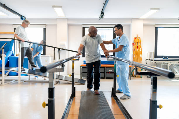 istock Diverse senior patients walking while leaning on parallel bars and the support of their physical therapists at a rehabilitation center 1594515147