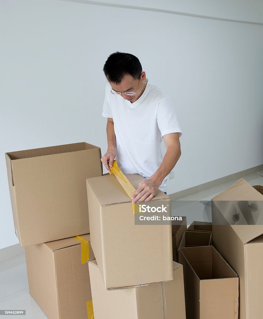 moving house Man tape the box for moving house. 20-24 Years Stock Photo