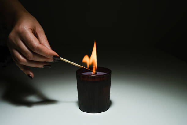 istock a burning match in a woman's hand lights a candle 1594584474