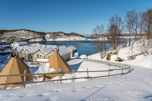 Country side, houses and tent,  in backgroundThe Saltstraumen Bridge across the fjord Saltfjorden in Bodo territory in Nordland country, Norway. Winter with snow.