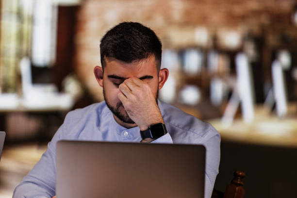istock Tried young man rubbing his temples while working at his desk 1594618977