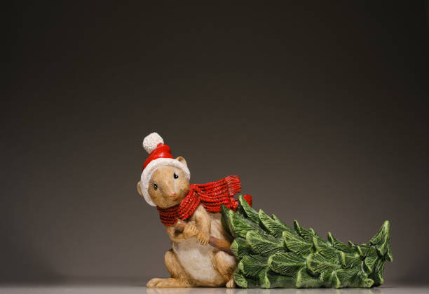 cute little mouse dressed as santa claus pulls the tree to his hole
