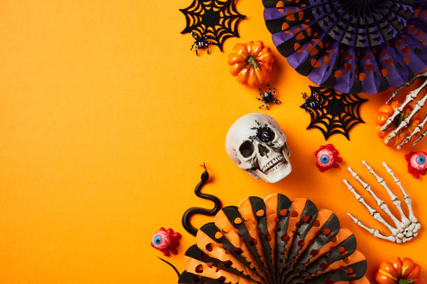 istock Halloween flat lay composition with skull, spider webs, snake, skeleton hands, paper fans on orange background. 1594633842
