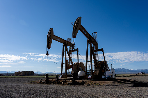 Two working oil pump jacks against the blue sky. Colorado, USA - May 17, 2023.