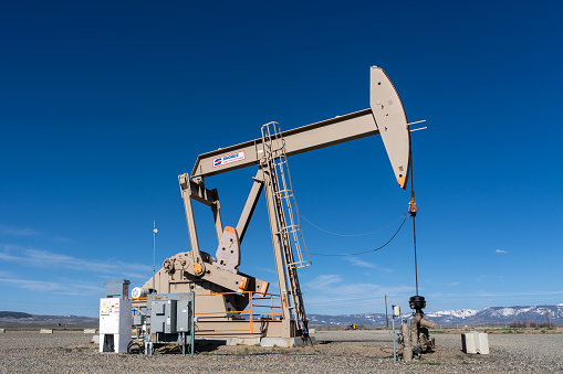 A working oil pump jacks against the blue sky. Colorado, USA - May 17, 2023.