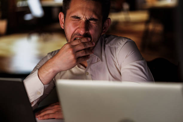 istock Tired young man yawning while working late at the office 1594660103