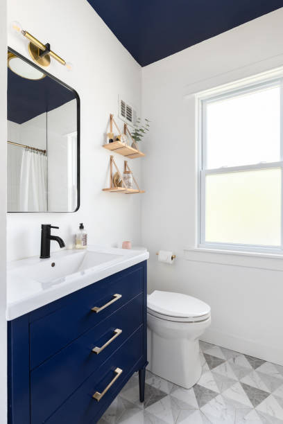 A bathroom with a blue cabinet and ceiling and pattern tile floor.