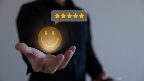 istock Businessman using a mobile phone to point to a smile face and five stars icon, representing positive reviews and customer satisfaction. Building credibility and trust with happy customers. 1594713367