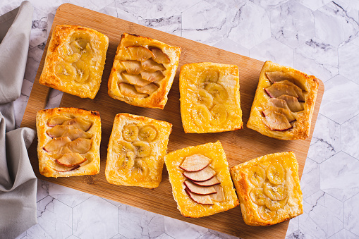 Small upside-down puff pastry tarts with apple and banana on the board top view