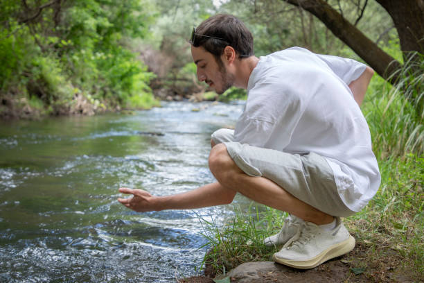 istock Young man tasting water by a river in nature 1594738717