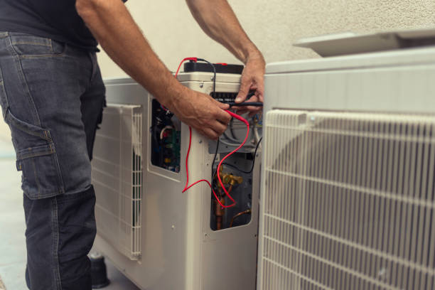 an unrecognizable electrician installs a heat pump in the courtyard of a residential building - huisverwarming fotos stockfoto's en -beelden