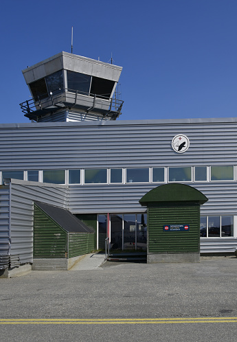 Nuuk / Godthab, Greenland: Nuuk Airport (IATA: GOH, ICAO: BGGH) - control tower and metal-clad façade, seen from the apron - logo of the airport operator, the Greenland Airport Authority (Mittarfeqarfiit / Grønlands Lufthavne).