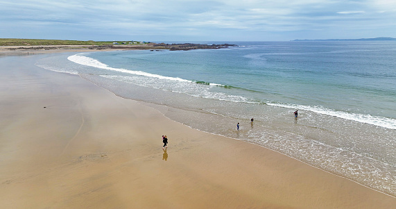 Aerial view of a family having fun on a sandy beach on the Atlantic Ocean in County Donegal Ireland