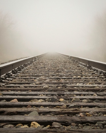 Railroad tracks in one point perspective vanishing into fog