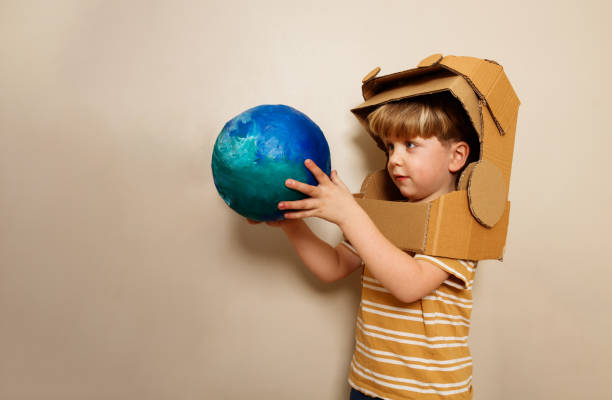 istock A child with cardboard astronaut helmet holds earth globe 1594924068