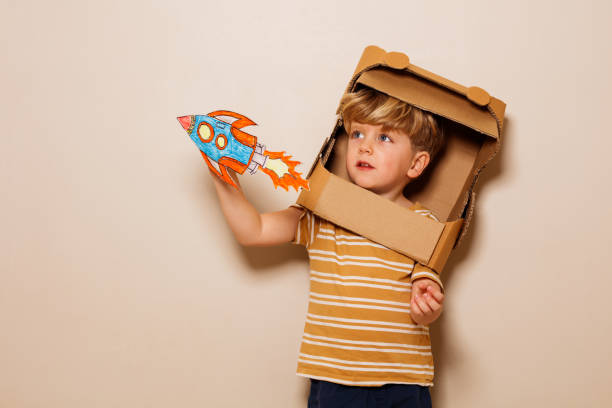 istock Boy play with paper rocket wears cardboard helmet space dreaming 1594924598