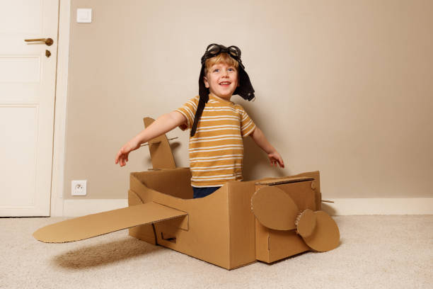 istock Boy play cardboard plane, wears hat, glasses pretends to fly 1594924599