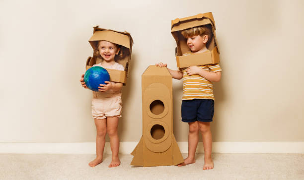 istock Happy kids play astronauts hold earth model and cardboard rocket 1594924601