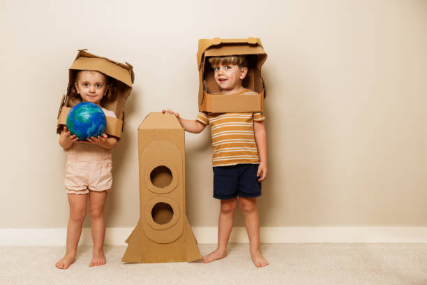 istock Kids with cardboard rocket and helmets hold model planet earth 1594924611