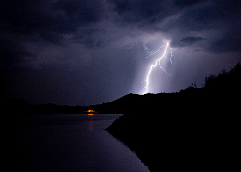 Lightning bolts striking with silhouetted hills at at Lake Mead Nevada