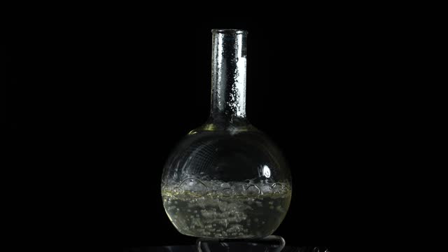 Liquid boils in a laboratory flask. Do drugs in the lab. Slow motion