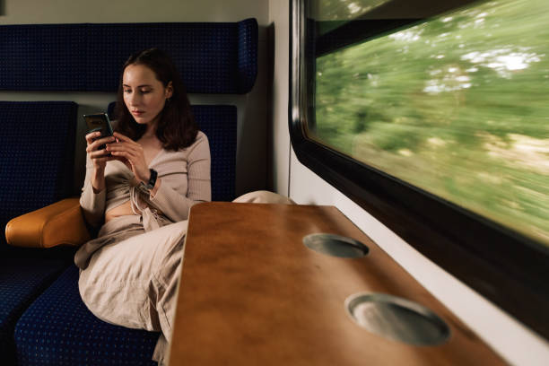 istock Female portrait of passenger who using mobile phone in train 1595036049