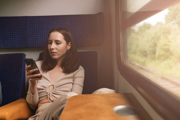 istock Female portrait of passenger who using mobile phone in train 1595036065
