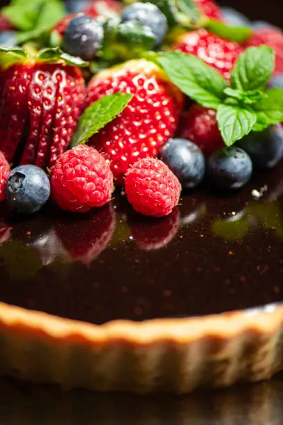 Delectable home made Chocolate Tart with rich shortcrust pastry, flourless chocolate cake, creamy ganache and dark chocolate icing, topped with fresh berries.