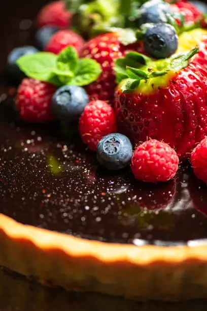 Delectable home made Chocolate Tart with rich shortcrust pastry, flourless chocolate cake, creamy ganache and dark chocolate icing, topped with fresh berries.