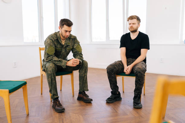 istock Front view of bearded Caucasian soldier male suffering depression sharing thoughts with group of people sitting in circle during PTSD group therapy session. 1595085948