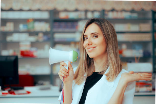 istock Happy Pharmacist Showing with her Hand Speaking on a Megaphone 1595091267